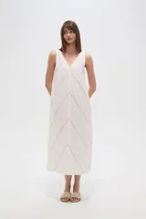 Vestido midi de algodón color crudo, con cuello en V, sin mangas y diseño holgado. Presenta un delicado bordado lineal en forma de zigzag que recorre toda la prenda.