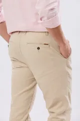 Pantalón de lino color beige, de corte recto y cintura elastizada con presillas para cinturón y bolsillos laterales.