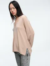 Sweater de punto gris con escote en V profundo, hombros caídos y mangas largas. Presenta un diseño de calce relajado con sutiles micro lentejuelas integradas en el tejido.