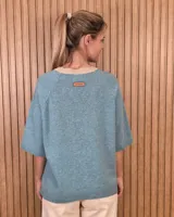 Buzo de punto color celeste con cuello en V de color beige, mangas cortas y diseño holgado.