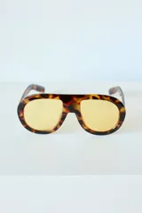 Lentes de sol con armazón de policarbonato con estampado carey y cristales amarillos. Diseño de estilo aviador con puente superior recto.