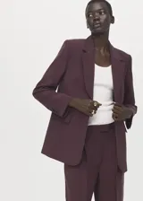 Blazer de diseño recto estilo traje, color bordó, confeccionado en tejido de lyocell. Cuenta con cuello pico con solapa de muesca, manga larga con puños abotonados, dos bolsillos laterales con solapa y cierre frontal de un botón.