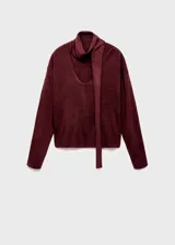 Jersey de punto fino color bordó, de diseño recto con escote en V y manga larga. Cuenta con un adorno de fular integrado en el cuello.