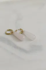 Aros tipo argolla con dije colgante en forma de gota de piedra natural en tonos marrones. Fabricados en acero quirúrgico dorado.