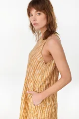 Vestido midi verde de lino italiano, con diseño sin mangas, cuello redondo y estampado de líneas onduladas punteadas. Cuenta con bolsillos laterales.