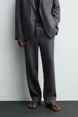 Pantalón de traje regular fit confeccionado en tejido de lino, con cierre frontal de cremallera y botón, bolsillos laterales y bolsillos traseros de vivo.