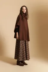 Poncho de tejido de punto color gris, con cuello alto y mangas amplias de diseño holgado.