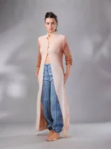 Saco largo tejido de lana Merino natural con diseño jacquard de ramas. Cuenta con cuello alto, cierre frontal con botones pequeños, mangas largas con puños entallados y aberturas laterales. Su diseño versátil permite usarlo abierto, cerrado como vestido o ajustado.