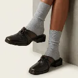 Zueco de cuero vacuno color negro, con diseño de nudo en el empeine y punta cuadrada. Cuenta con un taco bajo de madera y suela de cuero.