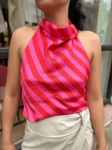 Blusa estampada a rayas diagonales en tonos rojo y fucsia, con cuello buche y diseño sin mangas de corte halter.
