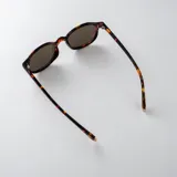 Lentes de sol con armazón carey de diseño redondo, con detalles metálicos dorados en las bisagras y cristales oscuros.