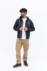 Campera de felpa azul marino con cierre frontal, capucha ajustable con cordones blancos y bolsillos canguro. Presenta un pequeño parche estampado en el pecho izquierdo.