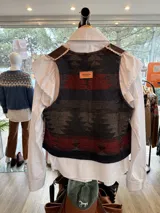 Chaleco artesanal con frente de cuero y espalda de tejido con patrón geométrico estilo Pendleton. Presenta detalles de bordado a mano en los bordes y etiqueta de marca Antonia en la parte posterior.
