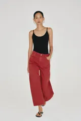 Jeans capri de tiro medio y pernera balloon, color rojo ladrillo. Confeccionados en denim, cuentan con trabillas en la cintura, bolsillos delanteros y traseros, y cierre frontal con cremallera y botón metálico.