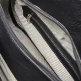 Cartera de hombro XL confeccionada en cuero vacuno con textura granulada. Presenta un diseño clásico con correa ajustable mediante hebilla metálica y placa frontal con el logo de la marca.