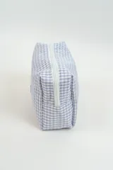 Neceser de tela con estampado de cuadros vichy en color verde y blanco. Cuenta con una etiqueta frontal con el logo de la marca y un tirador de cierre en color rosado.