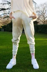 Pantalón de jogging color beige con efecto batik, confeccionado en tejido rústico. Presenta bolsillos diagonales laterales, cintura y botamanga con puño, y detalle bordado de la marca en el bolsillo.