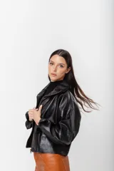 Chaqueta tipo bomber de cuero color suela con acabado rústico, cuello amplio, cierre frontal y mangas caídas de corte holgado.