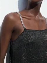 Vestido negro con estampado de ondas plateadas y tirantes de cadena metálica.