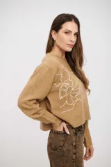 Sweater de tejido de punto color tostado, con cuello redondo, mangas largas con puños acanalados y diseño holgado. Presenta un delicado bordado lineal de una flor en el frente.