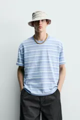 Remera relaxed fit con diseño de rayas horizontales en tonos celestes y blancos, cuello redondo y manga corta, con efecto lavado.