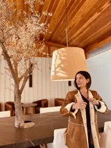 Gamulán color marrón con interior de corderito blanco, corte slouchy, cuello solapa y cierre frontal con broches. Presenta tajos laterales para mayor movilidad.