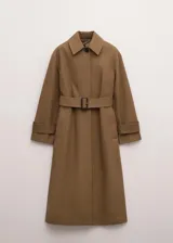 Chaqueta larga de algodón color marrón tostado, estilo gabardina, con cuello camisero, cierre frontal oculto con botones, mangas largas con presillas en los puños y cinturón ajustable con hebilla oscura.