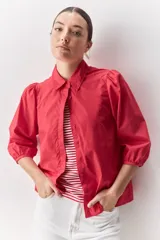 Camisa blanca de algodón, de calce relajado, con cuello camisero, frente abotonado y mangas largas abullonadas.