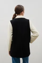 Blazer de lana con diseño bicolor, cuerpo en color negro y mangas en color crema. Presenta un corte holgado, cierre cruzado con doble botonadura y solapas amplias en contraste.