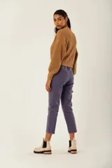 Saco de tejido de punto grueso color gris azulado, con cuello en V y manga larga abullonada. Presenta un solo botón de madera en la parte inferior delantera.