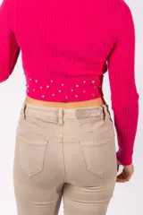 Campera de punto acanalado color fucsia, de corte cropped y manga larga. Presenta cierre frontal con tirador decorativo y detalle de tachas metálicas circulares en la parte inferior.