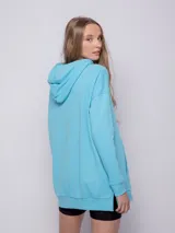 Canguro blanco oversize con capucha, cordones y bolsillo tipo canguro.