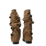 Bota de caña alta slouchy confeccionada en material símil gamuza color tostado, con diseño arrugado y múltiples tiras con hebillas metálicas en el lateral. Cuenta con taco bajo y suela negra.