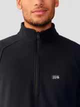 Buzo polar negro con cierre de un cuarto de longitud, cuello alto y mangas raglán, confeccionado en poliéster reciclado. Cuenta con un pequeño logo bordado de la marca en el pecho.