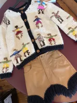 Cardigan de lana merino tejido con diseño de figuras humanas bordadas, cuello redondo, cierre frontal de botones y puños acanalados en color negro.