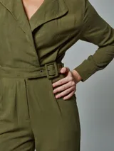 Mono enterito verde militar de lino, con solapas en el cuello, mangas largas y cinturón con hebilla forrada del mismo tono.