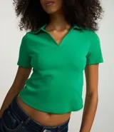 Blusa de cuello polo y manga corta, confeccionada en tejido rib de algodón con elastano. Presenta un diseño ajustado al cuerpo con escote en V y textura acanalada.