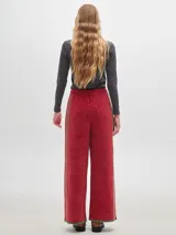 Pantalón ancho y suelto de tejido tipo terciopelo color naranja, con cintura elástica y cordón ajustable. Presenta detalles de pespuntes decorativos a los lados.