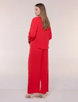 Blusa azul de corte holgado y fluido, con escote en V y mangas largas raglán que presentan detalles de calados con forma de flores y puños elastizados.