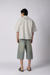 Camisa de manga corta de popelina con patrón a cuadros, calce boxy y largo a la cintura, con bolsillos y canesú cortados en diagonal.
