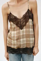Top lencero de escote en pico con tirantes finos ajustables. Presenta un estampado de cuadros en tonos beige y marrón, con detalles de encaje negro en el escote y en el ruedo.