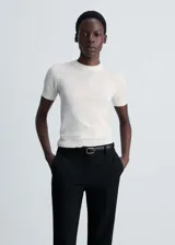 Jersey de punto fino color blanco crudo, de manga corta, con cuello redondo y diseño entallado.