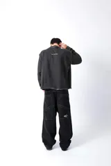 Buzo gris oscuro, estilo sweatshirt, con cuello redondo y terminaciones al corte en cuello, puños y cintura. Presenta un bordado en el frente.