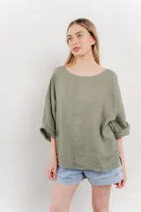 Blusa de lino color verde oliva, de corte amplio y relajado, con escote redondo y mangas 3/4 remangadas.