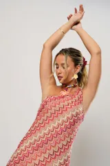 Vestido midi de crochet con diseño de ondas en tonos rojo, rosa y beige. Tiene un solo hombro y tajos laterales.
