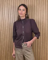 Camisa de algodón color blanco, con cuello alto con volados, mangas tres cuartos con detalles de bordado ingles y cierre frontal con botones de nácar.