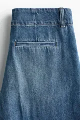 Jean de denim de algodón rígido, color azul con efecto lavado, de tiro alto y corte recto holgado. Cuenta con bolsillos al bies y pliegues marcados al frente y en la espalda.