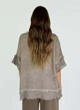 Blusa celeste de lino con escote en V y mangas cortas con volados. Tiene terminaciones desflecadas en el escote, mangas y ruedo.