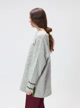 Sweater gris de punto con diseño de rombos, cuello redondo y mangas largas. Cuenta con puños largos acanalados con rayas horizontales en color verde militar y un pequeño logo bordado en el pecho.