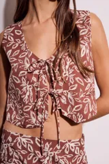 Chaleco marrón con estampado de hojas blancas, escote en V y lazos ajustables en el frente.